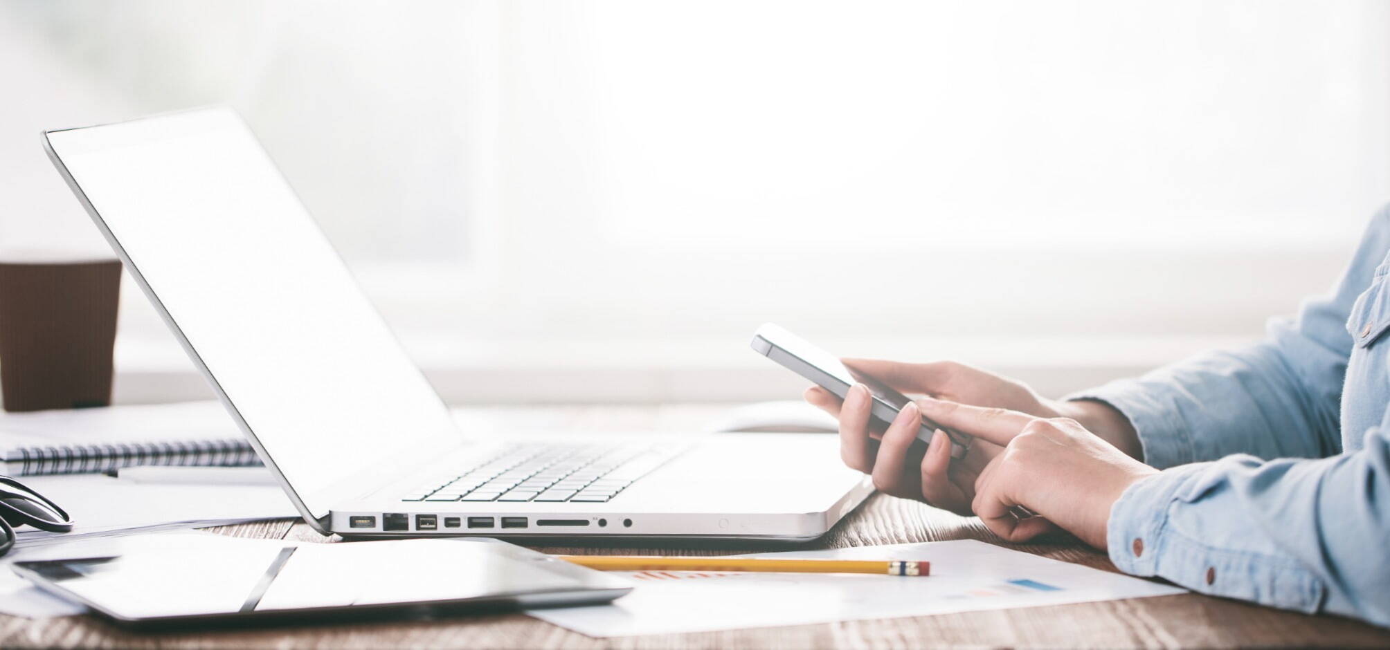 recruiter holding a phone in front of laptop hard at work at a desk