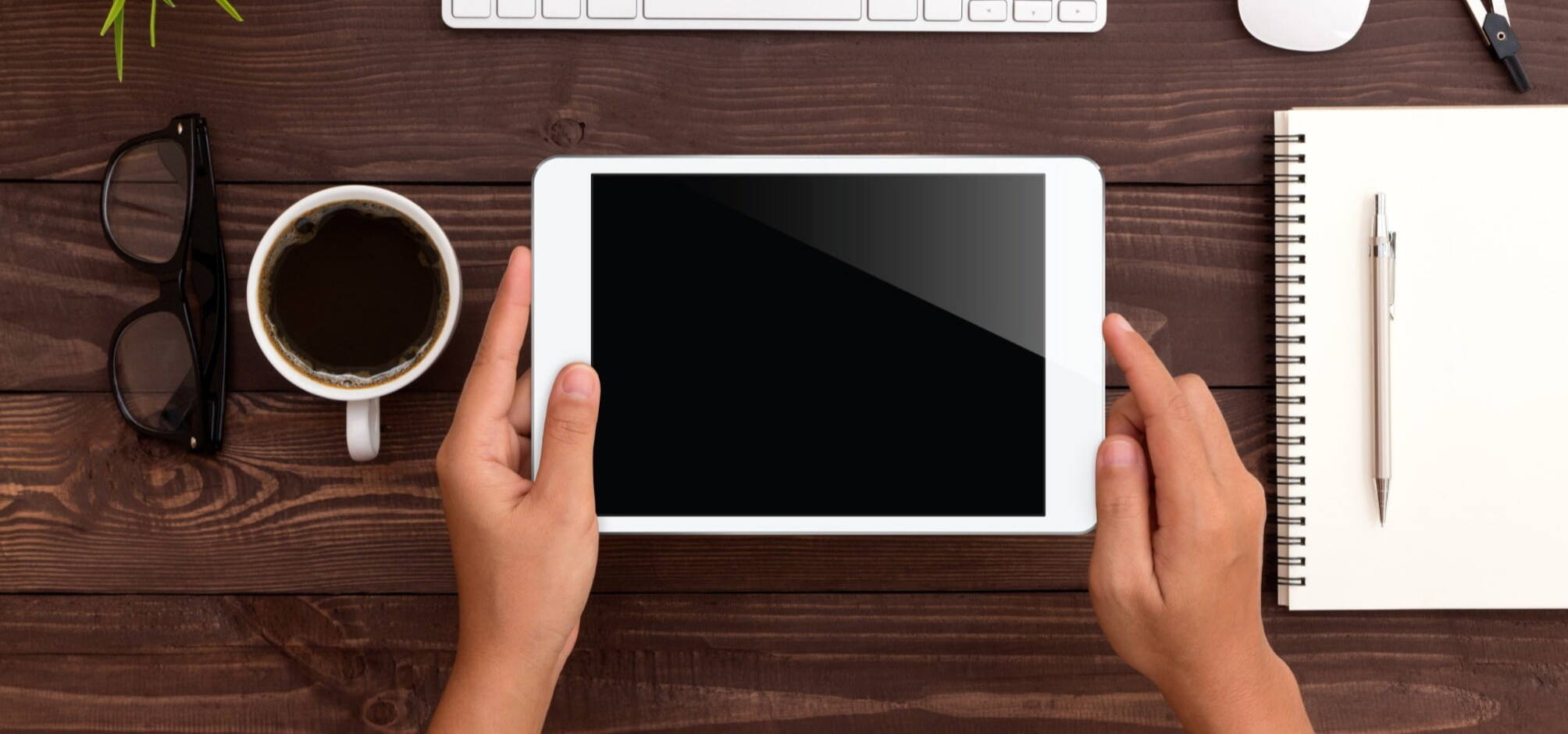 person holding a tablet on top of a desk in birdeye's view