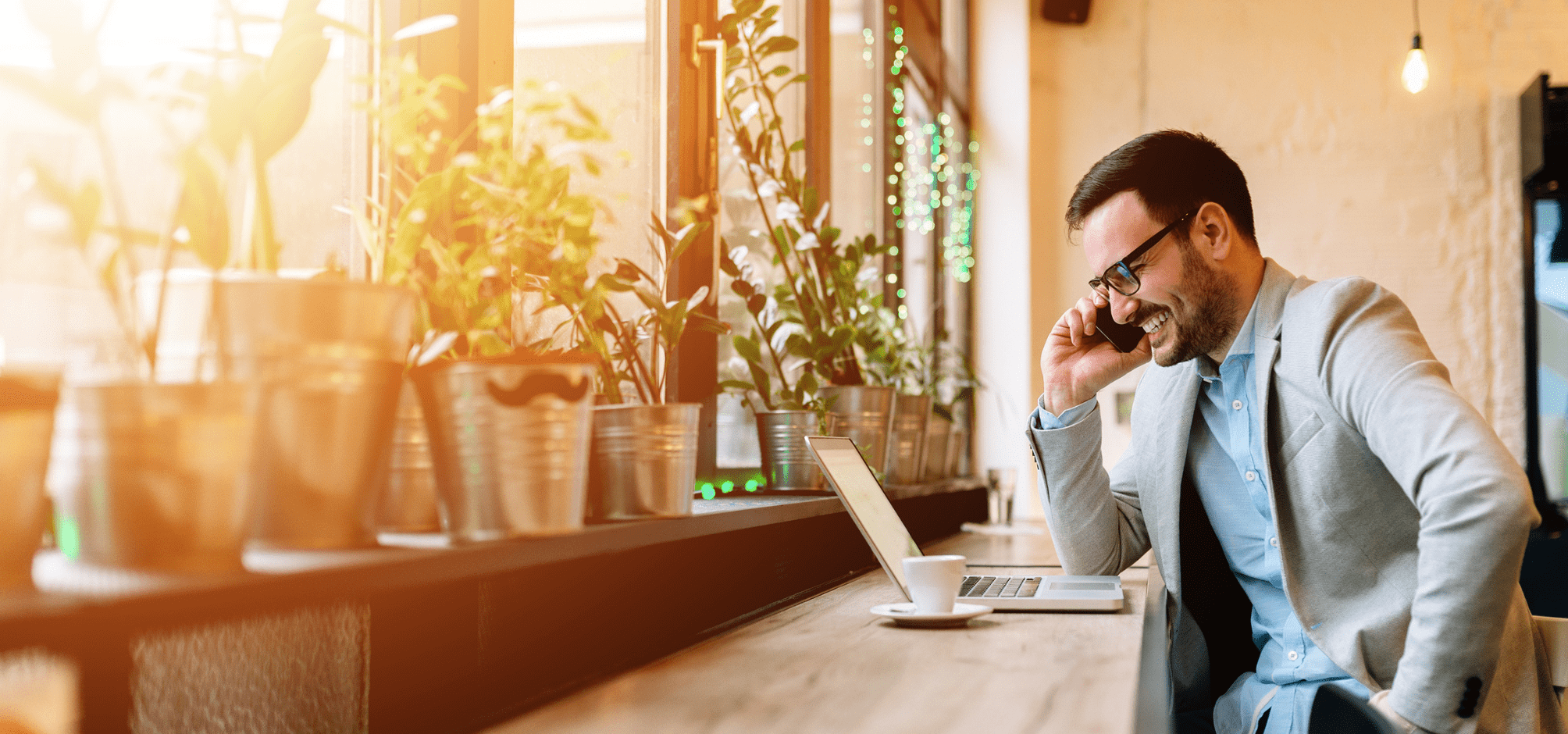 Man smiling while on the phone and looking at website on laptop