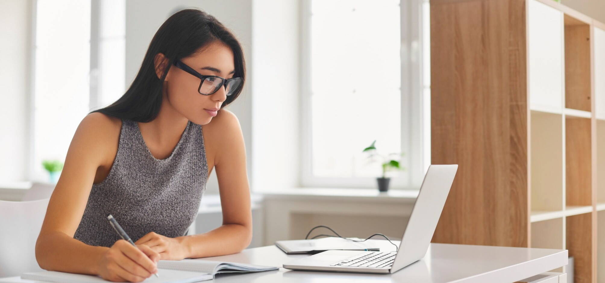 female recruiter looking at laptop screen while writing on a notepad